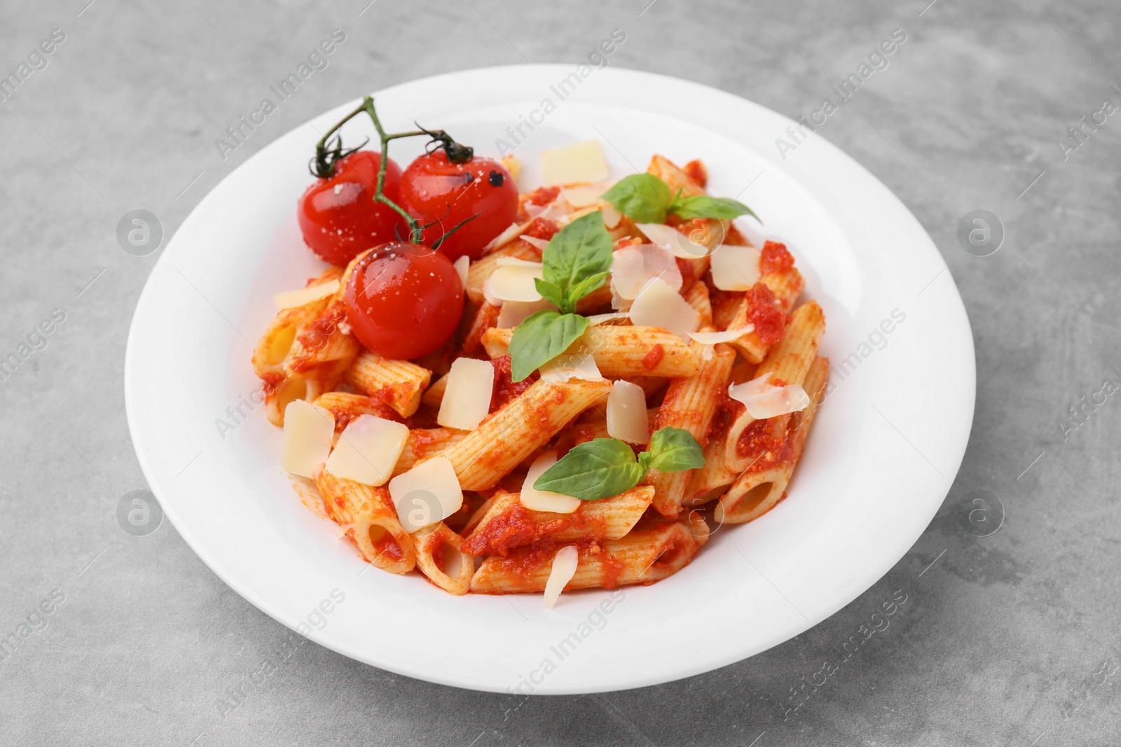 Photo of Tasty pasta with tomato sauce, cheese and basil on grey table