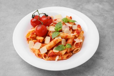 Photo of Tasty pasta with tomato sauce, cheese and basil on grey table