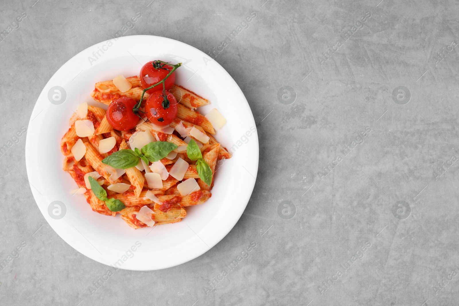 Photo of Tasty pasta with tomato sauce, cheese and basil on grey table, top view. Space for text