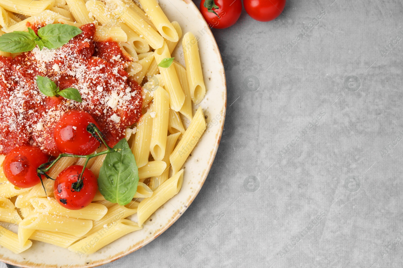 Photo of Tasty pasta with tomato sauce, cheese and basil on grey table, top view. Space for text