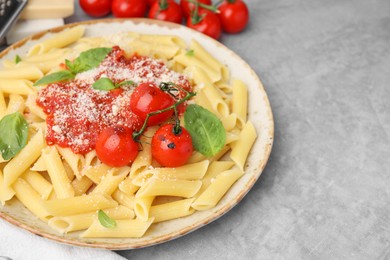 Photo of Tasty pasta with tomato sauce, cheese and basil on grey table, space for text