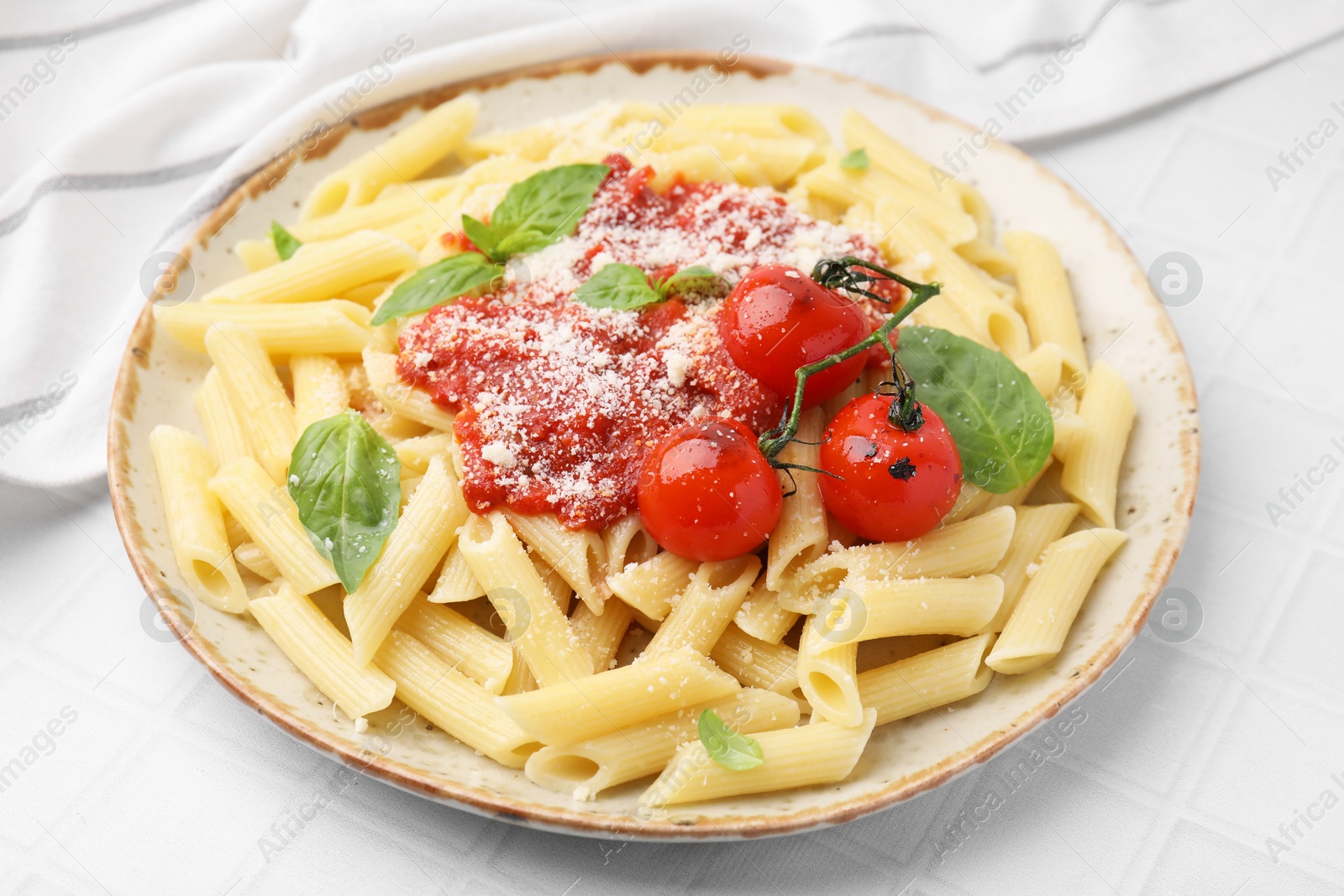 Photo of Tasty pasta with tomato sauce, cheese and basil on white tiled table