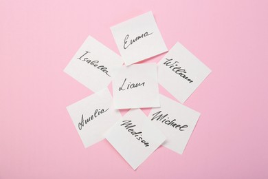 Photo of Paper stickers with different names on pink background, top view. Choosing baby's name