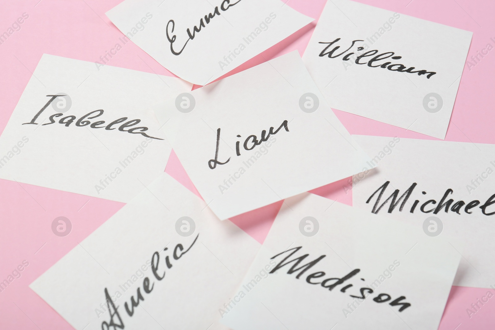 Photo of Paper stickers with different names on pink background, closeup. Choosing baby's name