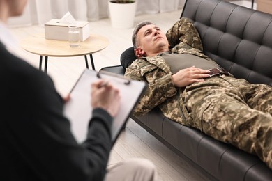 Photo of Professional psychotherapist working with military man in office