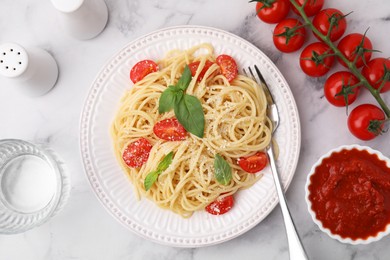 Tasty pasta with tomato, cheese and basil served on white marble table, flat lay