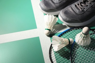 Feather badminton shuttlecocks, rackets and sneakers on court, above view. Space for text