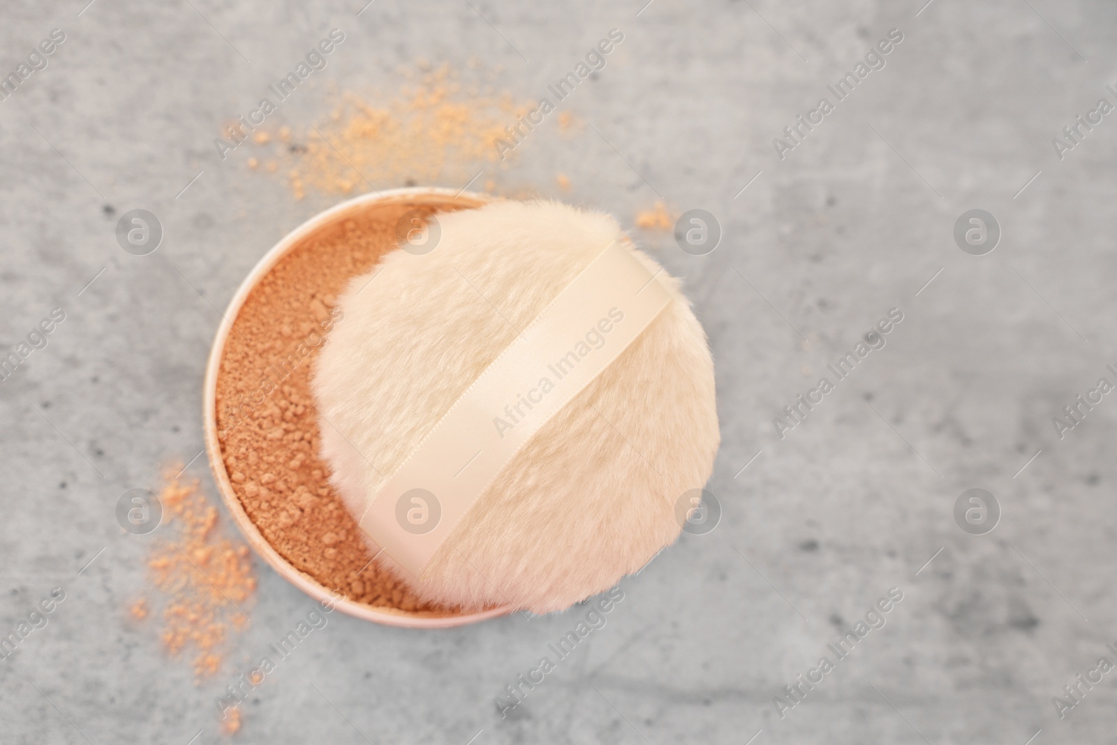 Photo of Face powder and puff applicator on grey textured table, top view. Space for text
