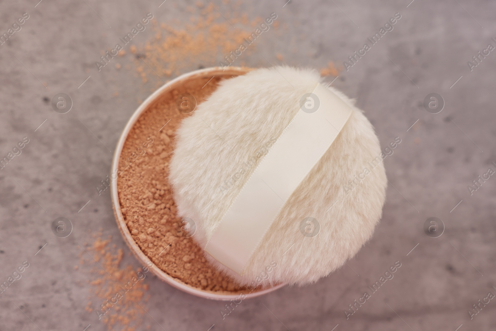 Photo of Face powder and puff applicator on grey textured table, top view