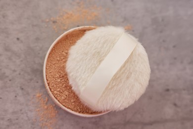 Face powder and puff applicator on grey textured table, top view