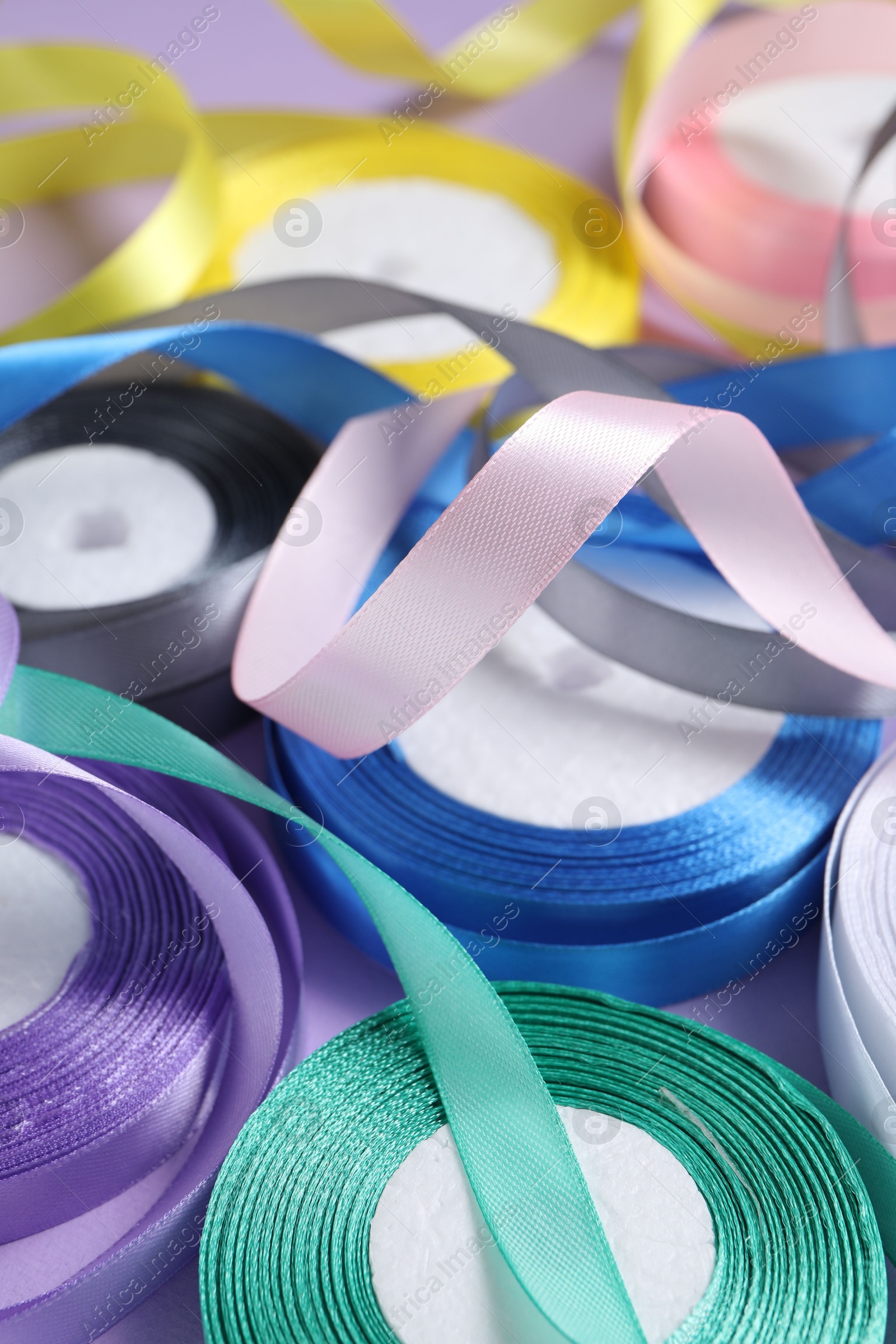 Photo of Ribbon reels in different colors on violet background, closeup