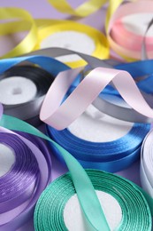 Photo of Ribbon reels in different colors on violet background, closeup