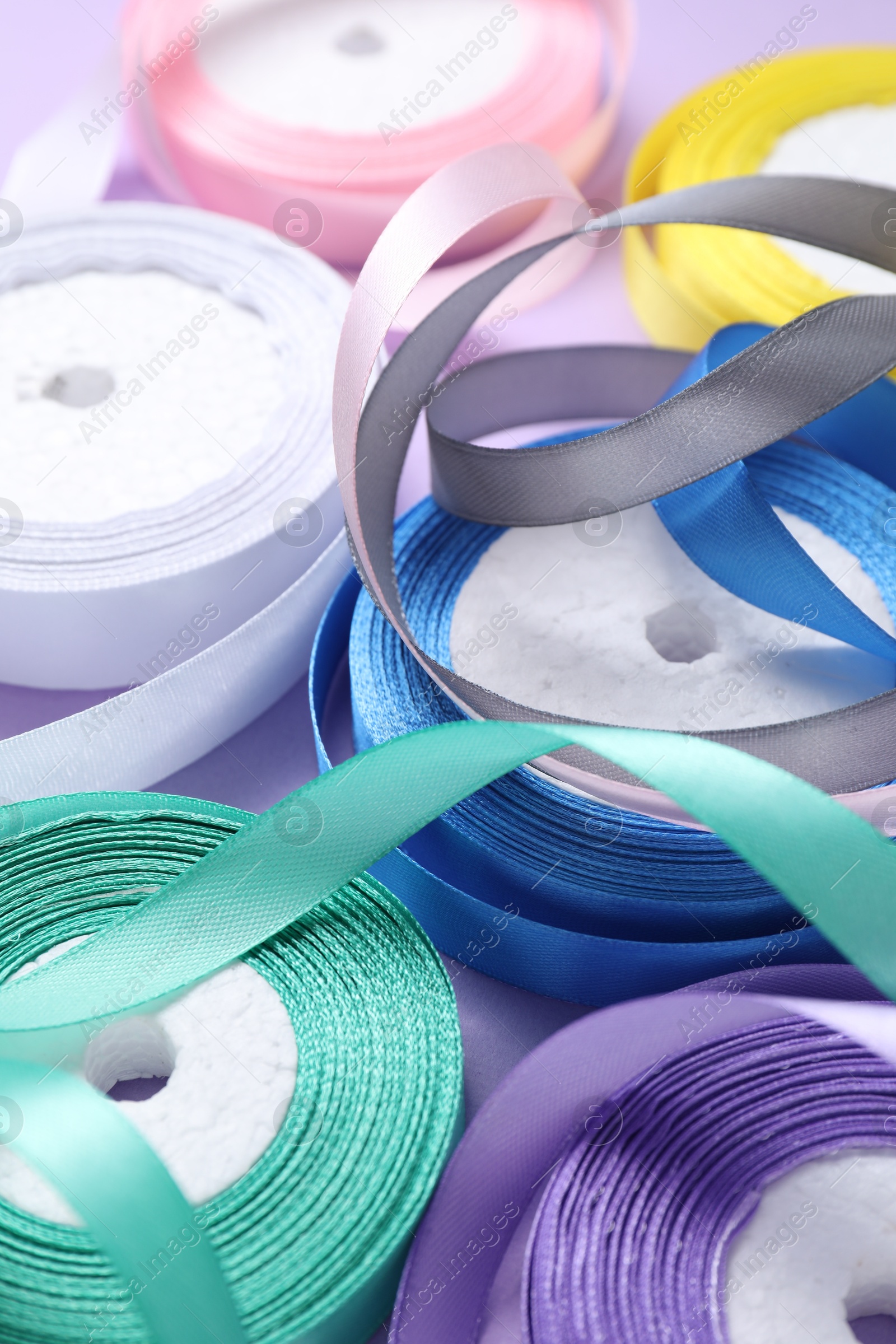 Photo of Ribbon reels in different colors on violet background, closeup