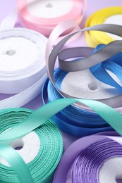 Ribbon reels in different colors on violet background, closeup