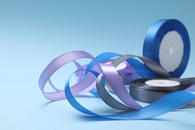 Photo of Ribbon reels in different colors on light blue background, closeup. Space for text