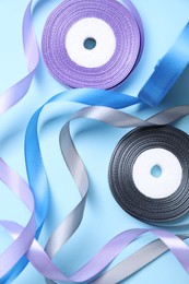 Ribbon reels in different colors on light blue background, flat lay