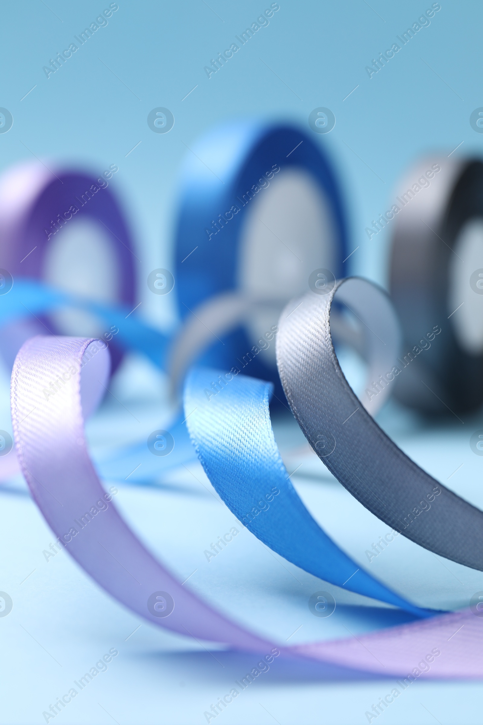 Photo of Ribbons in different colors on light blue background, closeup