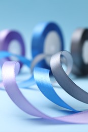 Photo of Ribbons in different colors on light blue background, closeup