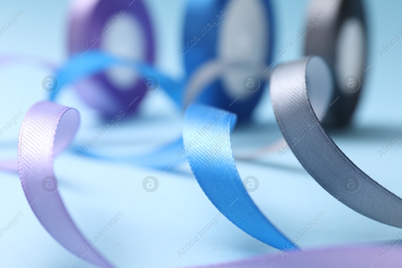 Photo of Ribbons in different colors on light blue background, closeup