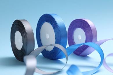 Ribbon reels in different colors on light blue background, closeup