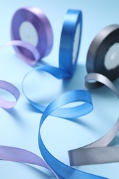 Ribbon reels in different colors on light blue background, closeup