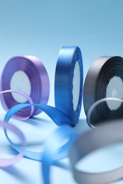 Photo of Ribbon reels in different colors on light blue background, closeup