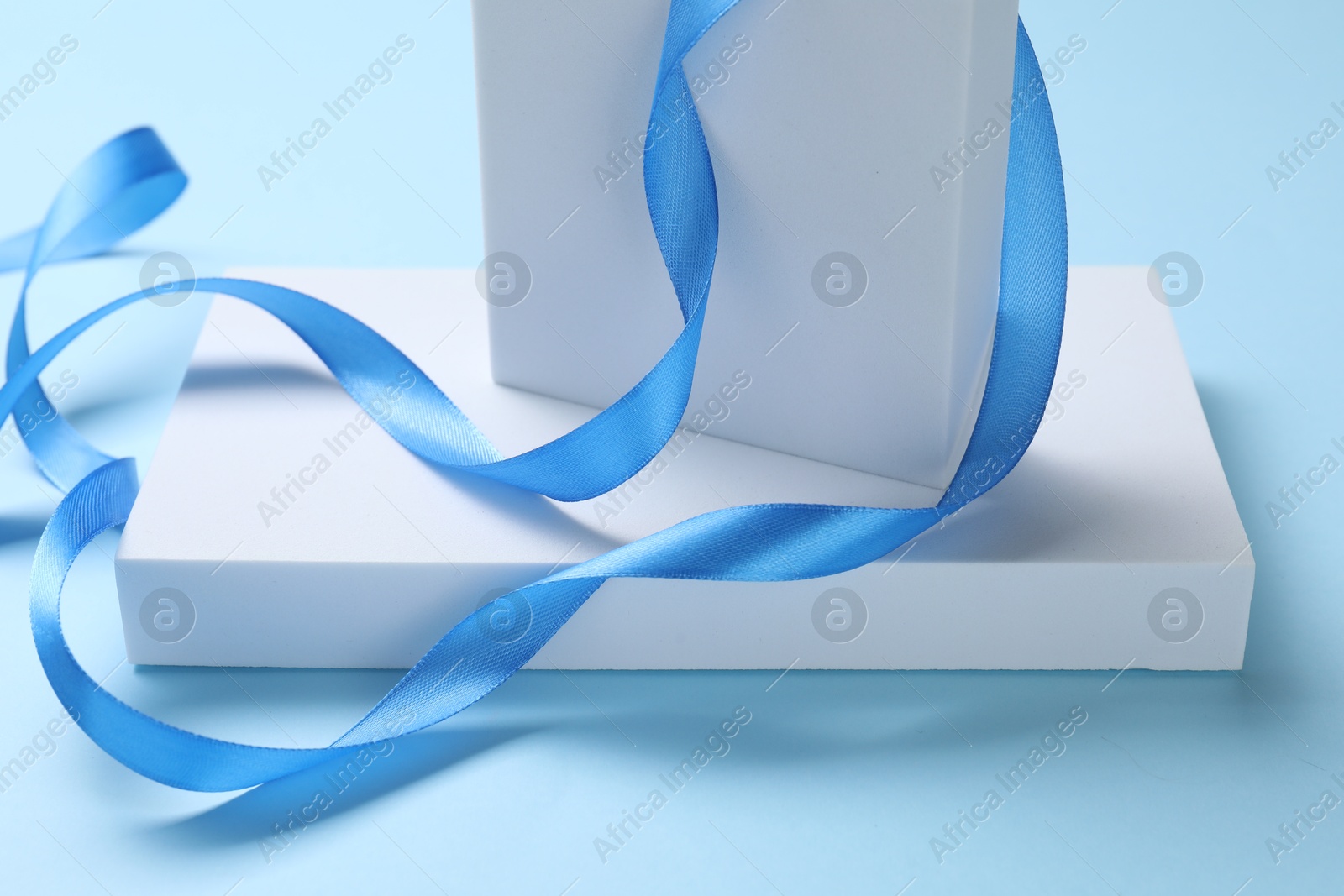 Photo of Beautiful bright ribbon and gift boxes on light blue background