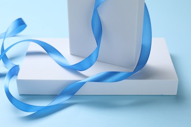 Photo of Beautiful bright ribbon and gift boxes on light blue background