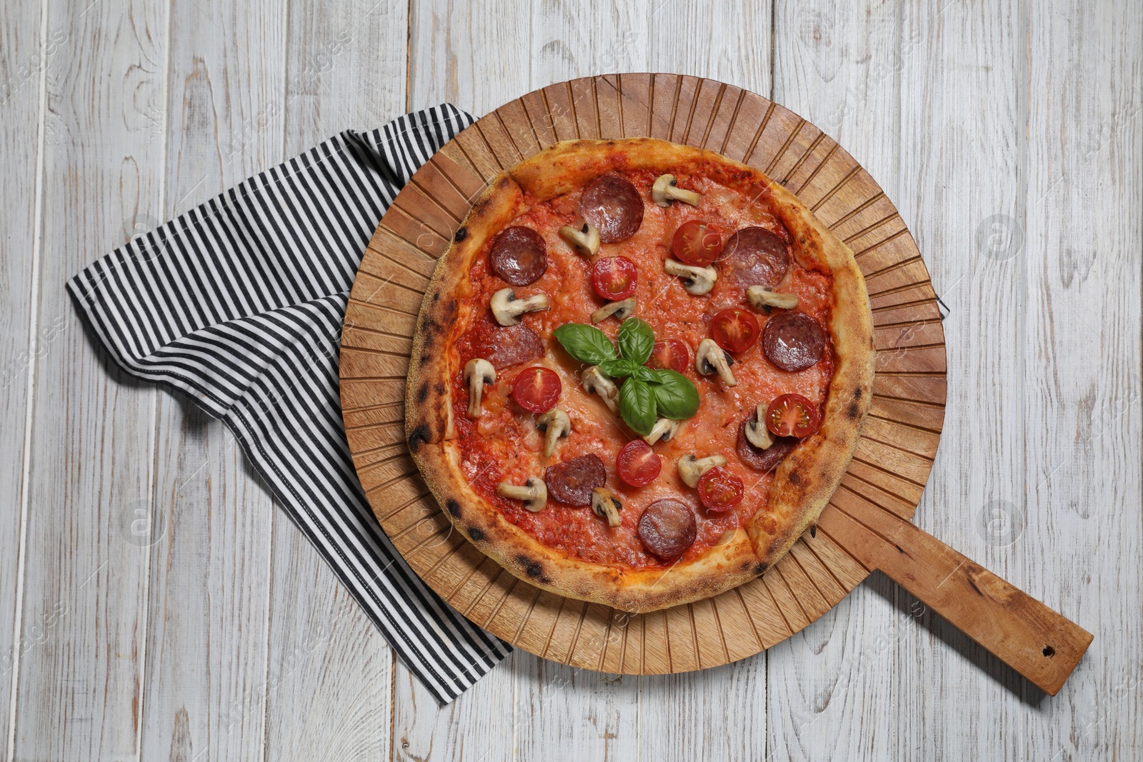 Photo of Delicious pizza with salami, tomatoes, mushrooms and basil on wooden table, top view