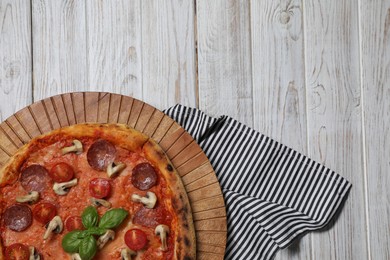 Photo of Delicious pizza with salami, tomatoes, mushrooms and basil on wooden table, top view. Space for text