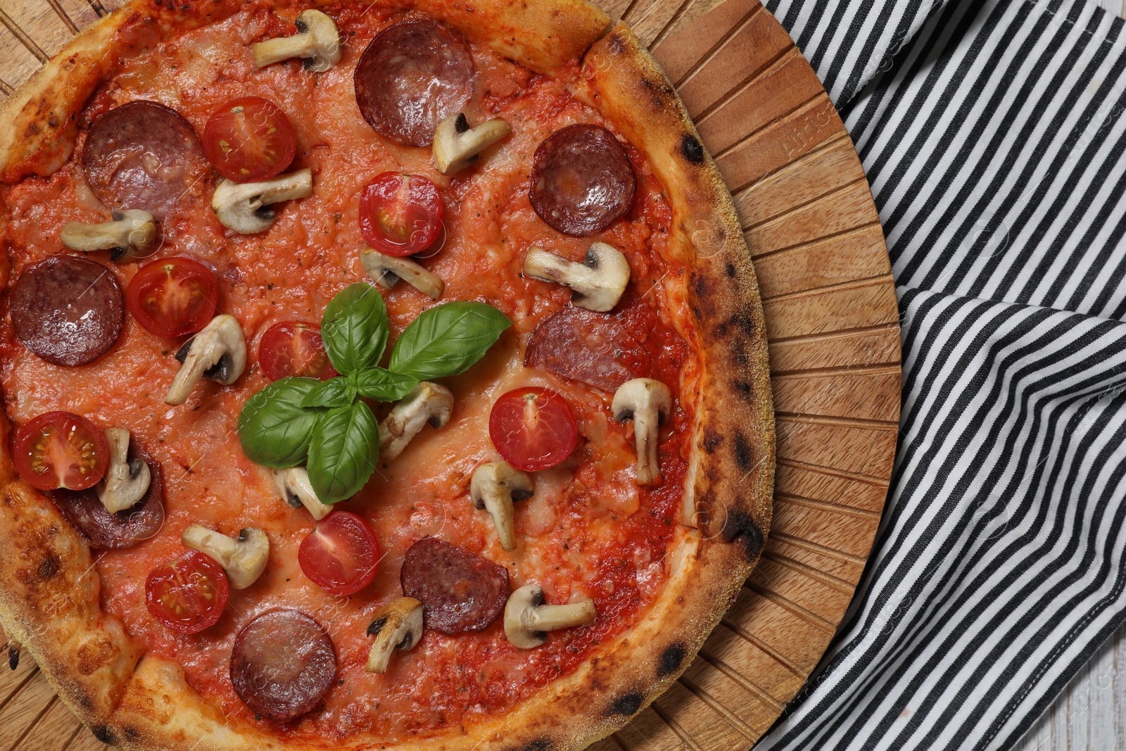 Photo of Delicious pizza with salami, tomatoes, mushrooms and basil on table, top view