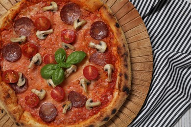 Photo of Delicious pizza with salami, tomatoes, mushrooms and basil on table, top view