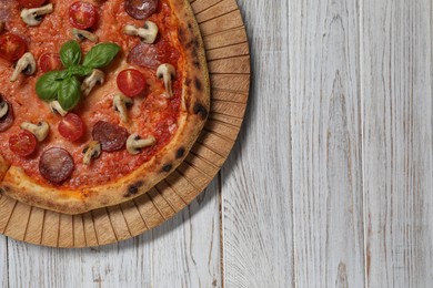 Photo of Delicious pizza with salami, tomatoes, mushrooms and basil on wooden table, top view. Space for text