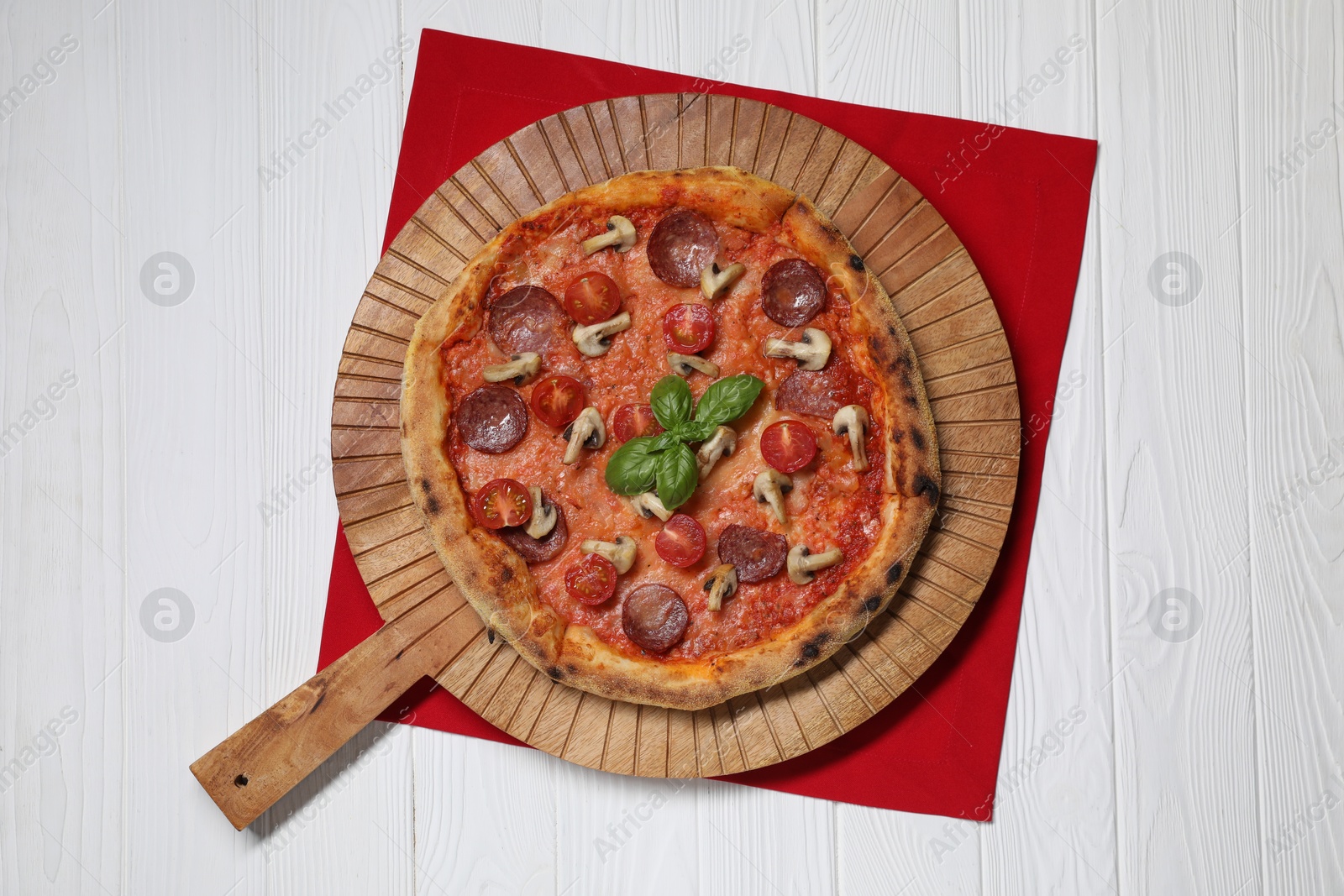 Photo of Delicious pizza with salami, tomatoes, mushrooms and basil on white wooden table, top view