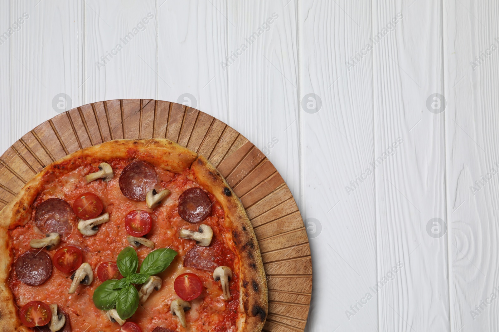 Photo of Delicious pizza with salami, tomatoes, mushrooms and basil on white wooden table, top view. Space for text