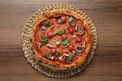 Photo of Delicious pizza with salami, vegetables, mushrooms and basil on wooden table, top view