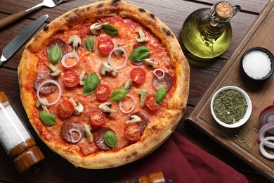 Photo of Delicious pizza with salami, vegetables, mushrooms and basil served on wooden table, flat lay