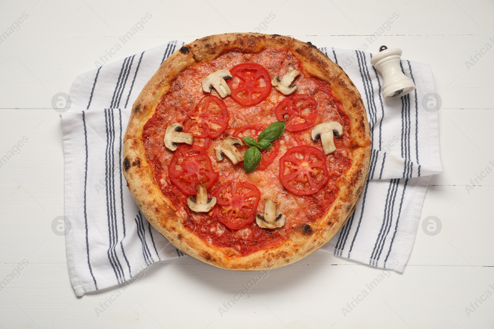 Photo of Delicious pizza with tomatoes, mushrooms and basil on white wooden table, top view