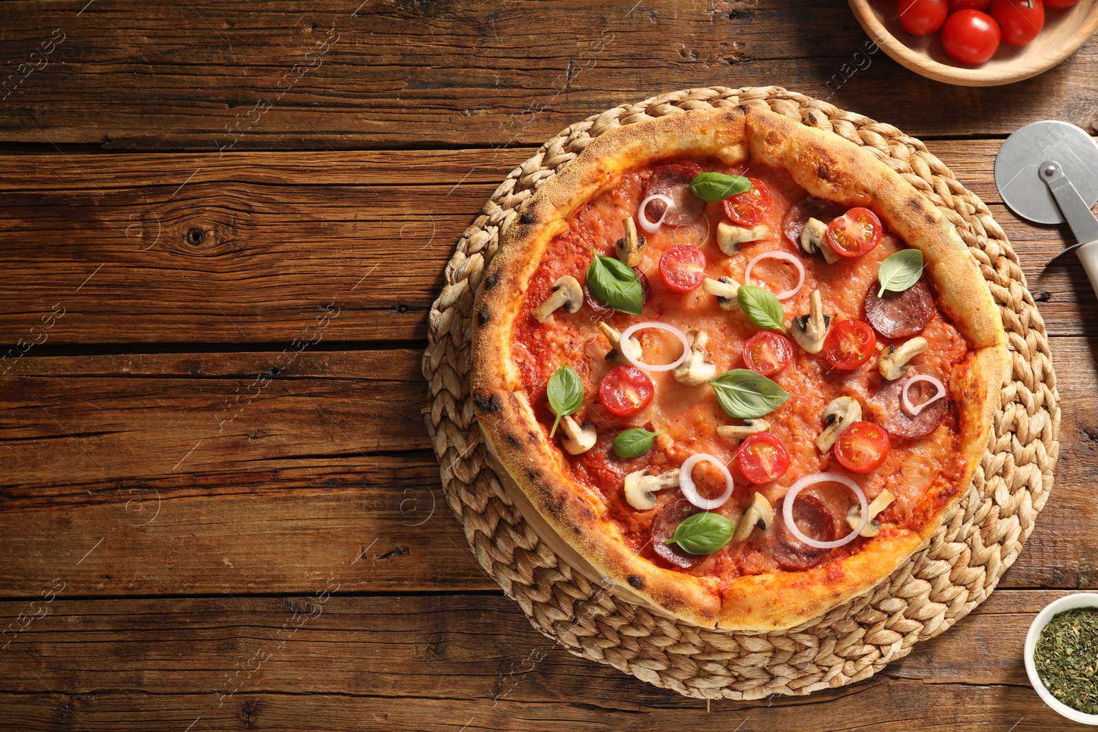 Photo of Delicious pizza with salami, vegetables, mushrooms and basil on wooden table, flat lay. Space for text