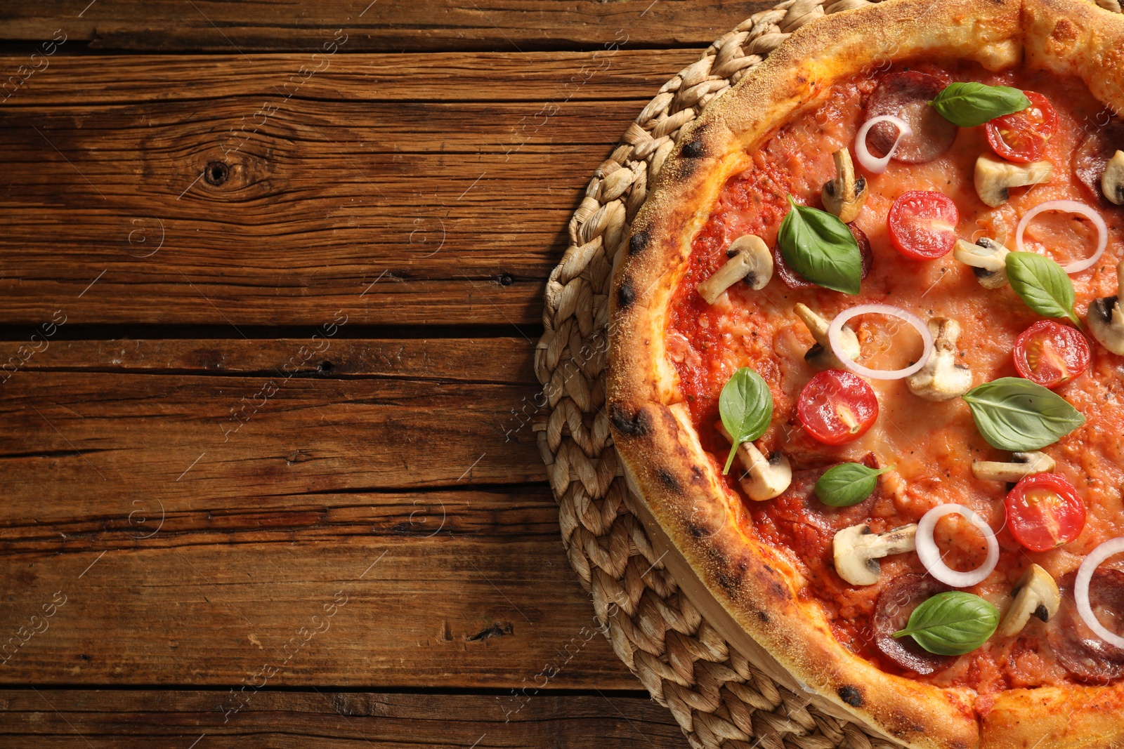 Photo of Delicious pizza with salami, vegetables, mushrooms and basil on wooden table, top view. Space for text