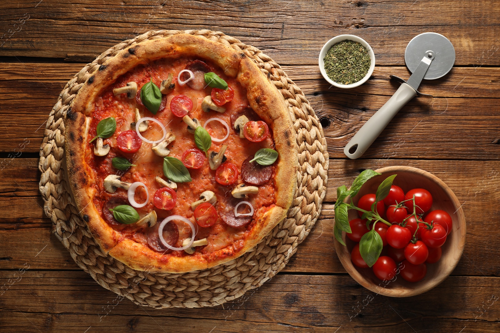 Photo of Delicious pizza with salami, vegetables, mushrooms and basil on wooden table, flat lay