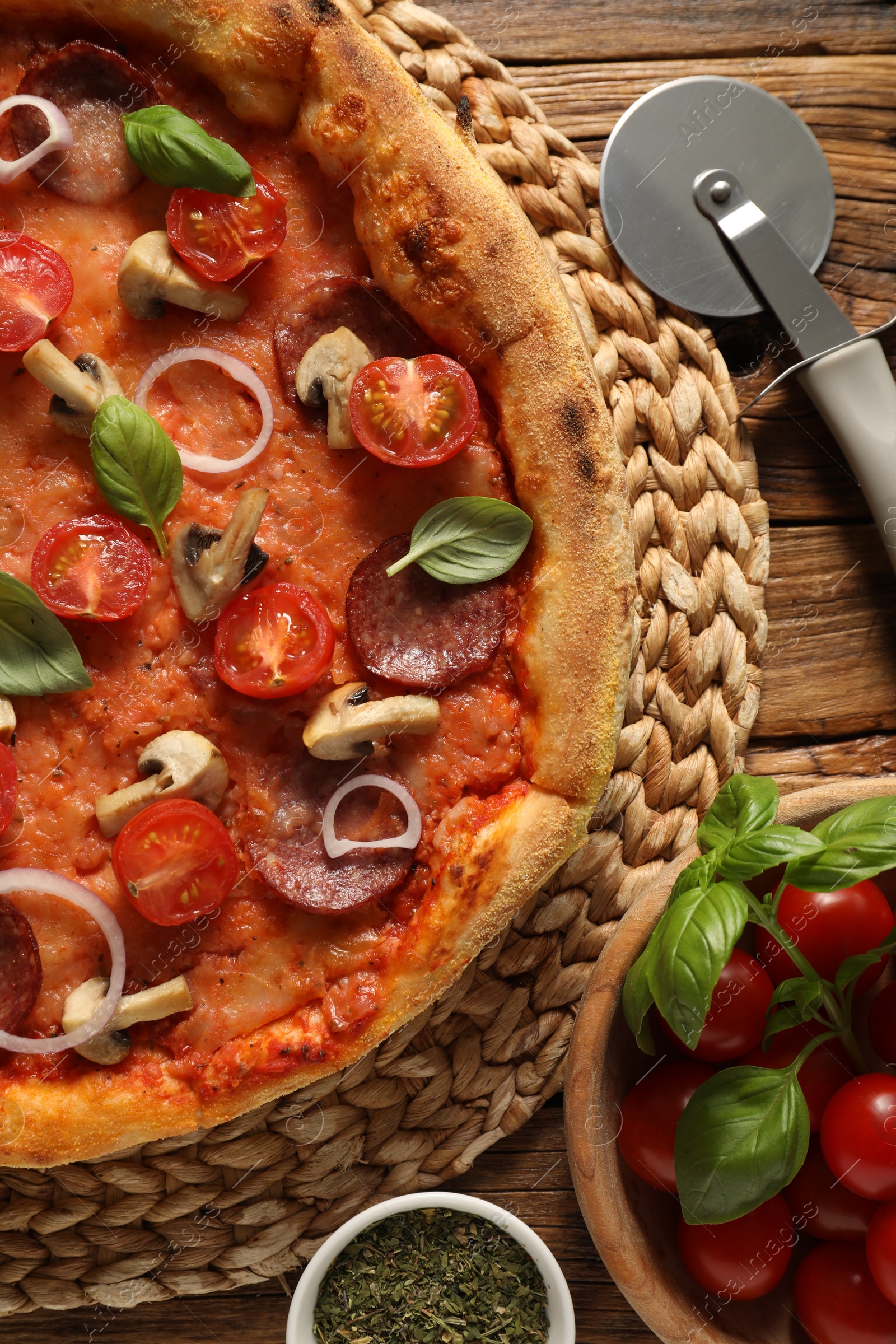 Photo of Delicious pizza with salami, vegetables, mushrooms and basil on wooden table, flat lay