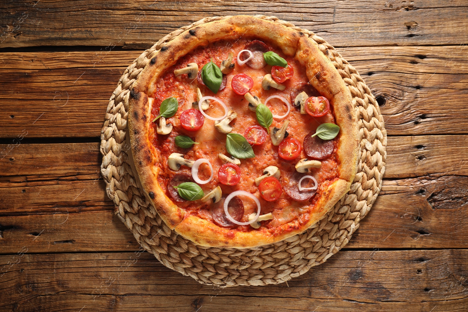 Photo of Delicious pizza with salami, tomatoes, mushrooms and basil on wooden table, top view