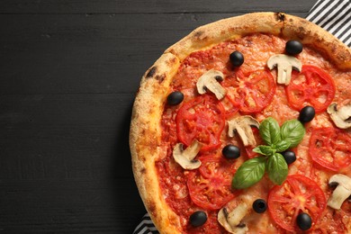 Photo of Delicious pizza with tomatoes, mushrooms, olives and basil on black wooden table, top view. Space for text