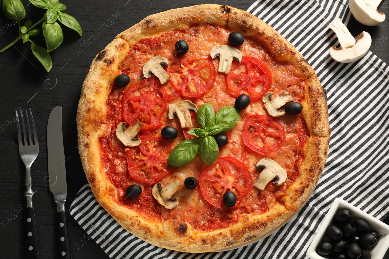 Photo of Delicious pizza with tomatoes, mushrooms, olives and basil served on black wooden table, flat lay