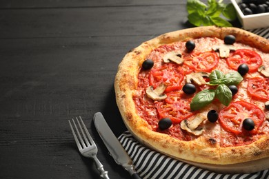 Delicious pizza with tomatoes, mushrooms, olives and basil served on black wooden table, closeup