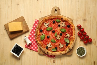 Delicious pizza with tomatoes, mushrooms, black olives and basil on wooden table, flat lay