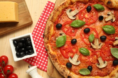 Photo of Delicious pizza with tomatoes, mushrooms, black olives and basil on wooden table, flat lay