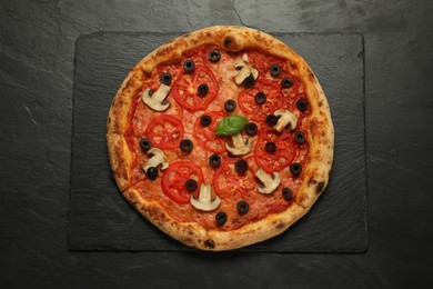 Photo of Delicious pizza with tomatoes, mushrooms, olives and basil on black textured table, top view