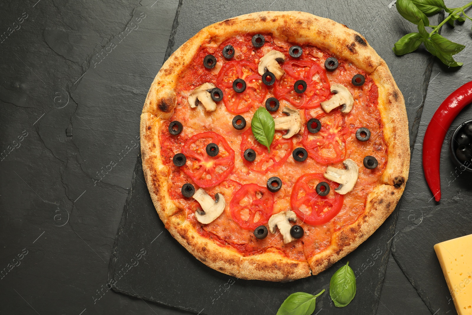 Photo of Delicious pizza with tomatoes, mushrooms, olives and basil on black textured table, flat lay. Space for text